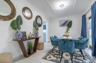 a dining room with blue chairs and mirrors at Greencroft Villa in Kempton Park