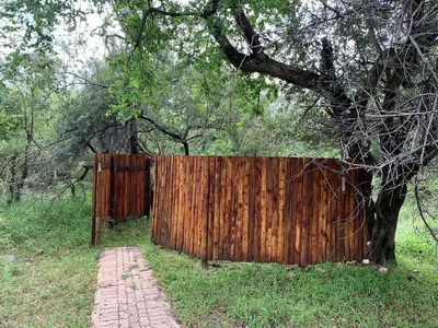 a wooden fence next to a tree in a field at Mabalingwe Elephant Lodge 256A in Moheme