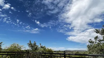 a blue sky with clouds and trees and a fence at 211 Zebula in Mabula