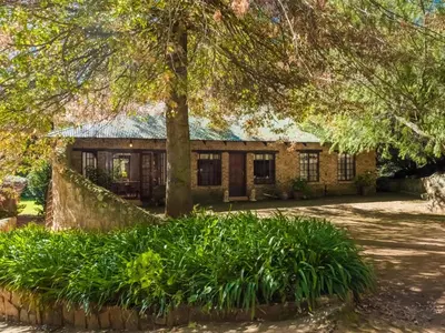 a brick house with a tree in front of it at Kinloch Lodge in Dullstroom