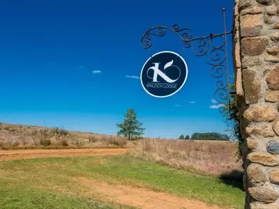 a sign on a stone wall next to a dirt road at Kinloch Lodge in Dullstroom