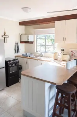 a kitchen with white cabinets and a wooden counter top at Country Side Cottage @ Low's Creek in Louwʼs Creek