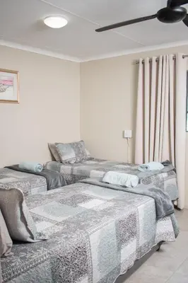 two beds in a room with a ceiling fan at Country Side Cottage @ Low's Creek in Louwʼs Creek