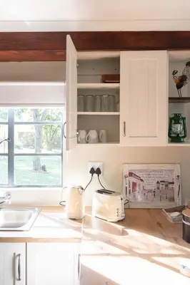 a kitchen counter with white cabinets and a window at Country Side Cottage @ Low's Creek in Louwʼs Creek