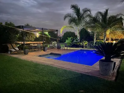 a swimming pool in a yard with a table and chairs at The Lodge on Ilona in Tierpoort