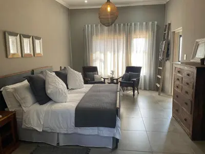 a bedroom with a bed and a table and chairs at The Lodge on Ilona in Tierpoort
