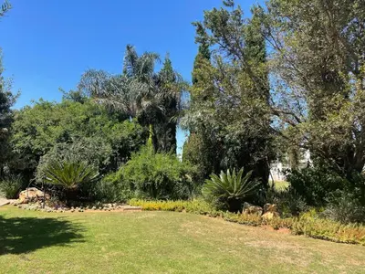 a garden with trees and grass and a field at The Lodge on Ilona in Tierpoort