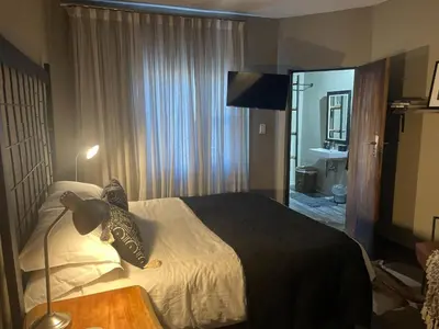 a hotel room with a bed and a lamp at The Lodge on Ilona in Tierpoort