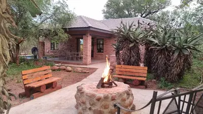 a fire pit in front of a house with two benches at Sonop in Marloth Park in Marloth Park