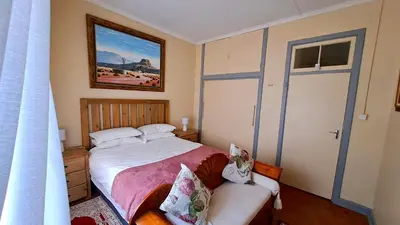 a small bedroom with a bed and a couch at Pine Forest Cottage in Sabie