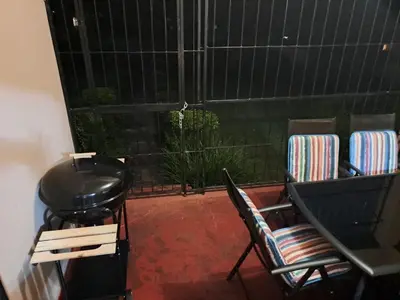 a balcony with chairs and a grill and a window at Pine Forest Cottage in Sabie