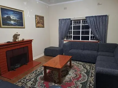 a living room with a couch and a fireplace at Pine Forest Cottage in Sabie