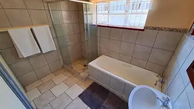 a bathroom with a tub and a toilet and a sink at Pine Forest Cottage in Sabie