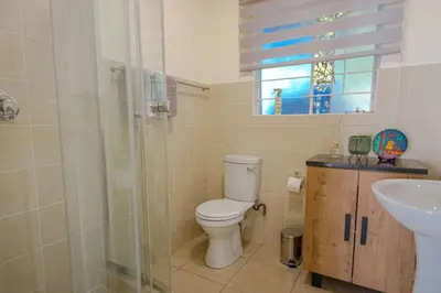 a bathroom with a toilet and a sink and a shower at The Lemon Tree Oasis - Solar in Centurion