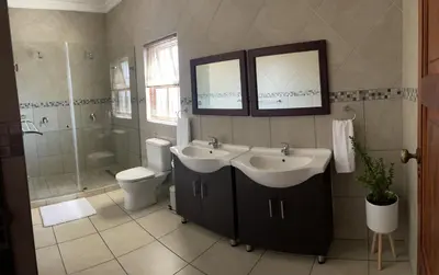 a bathroom with two sinks and a shower and a toilet at On-Nkwe accommodation in Tierpoort