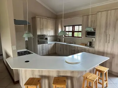 a kitchen with a white counter top and wooden cabinets at On-Nkwe accommodation in Tierpoort