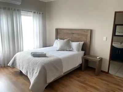 a bedroom with a bed with white sheets and a window at On-Nkwe accommodation in Tierpoort
