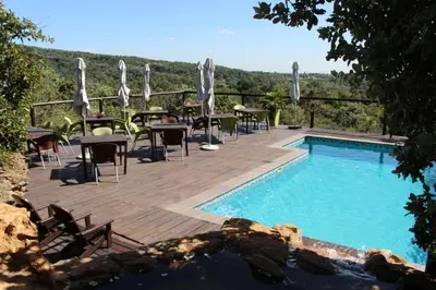 a pool with tables and chairs on a deck next to at Ndlovu Lodge in Pretoria