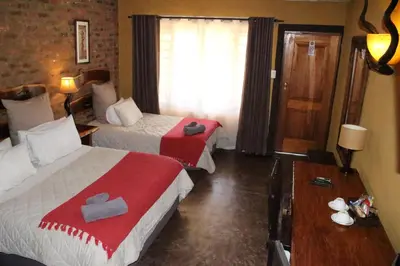 a hotel room with two beds with red and white sheets at Ndlovu Lodge in Pretoria