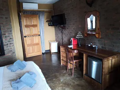 a bedroom with a bed and a desk and a mirror at Ndlovu Lodge in Pretoria