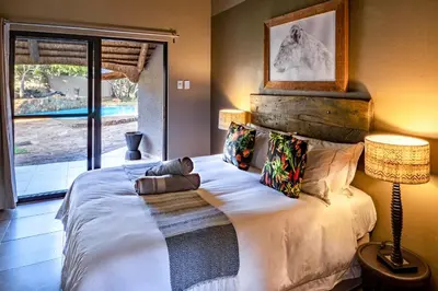 a bedroom with a large white bed with a window at Sable Ranch Bush Lodge in Brits
