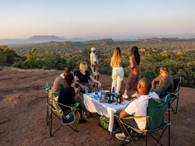 a group of people sitting around a table on top of a mountain at Sable Ranch Bush Lodge in Brits