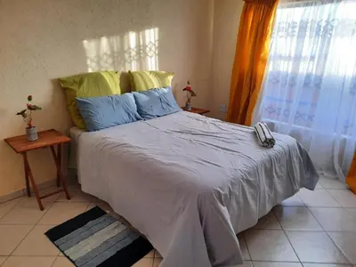 a bedroom with a large bed with blue and yellow pillows at Legaeng Cottage - Serenity in Pretoria