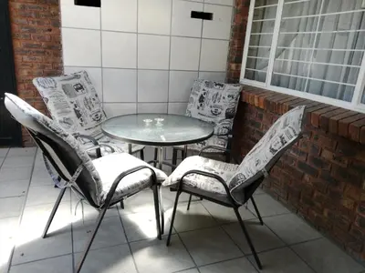 a group of chairs and a table on a balcony at Legaeng Cottage - Serenity in Pretoria