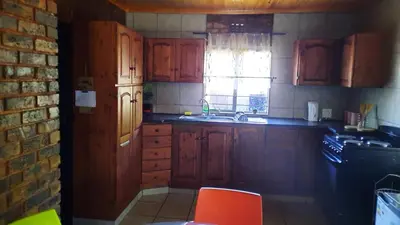 a kitchen with wooden cabinets and a sink and a window at Legaeng Cottage - Serenity in Pretoria