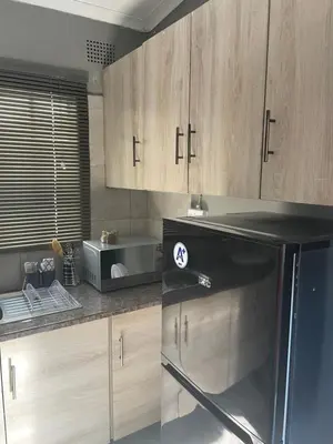 a kitchen with a black refrigerator and wooden cabinets at Solace Unit in Phalaborwa