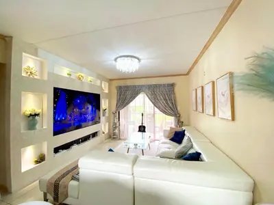 a living room with a white couch and a flat screen tv at Siena Sun Luxury Suite 1 in Midrand