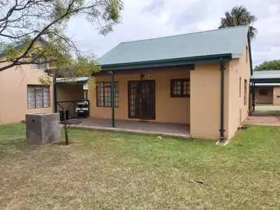 a small yellow building with a blue roof at Unit 24 Pendleberry Grove Holidays in Bela-Bela