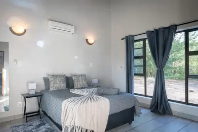 a bedroom with a bed and a large window at Nkanyi Wildlife House & Cottage in Hoedspruit