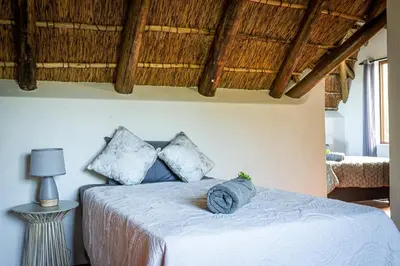 a bedroom with a bed with blue pillows at Nkanyi Wildlife House & Cottage in Hoedspruit