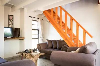 a living room with a couch and a staircase at Nkanyi Wildlife House & Cottage in Hoedspruit