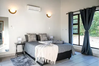 a bedroom with a bed and a large window at Nkanyi Wildlife House & Cottage in Hoedspruit
