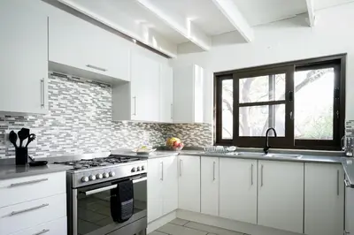 a white kitchen with white cabinets and a window at Nkanyi Wildlife House & Cottage in Hoedspruit