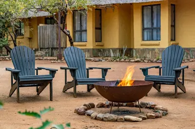 three chairs and a fire pit in a yard at Hoedspruit Bush Cottage in Hoedspruit