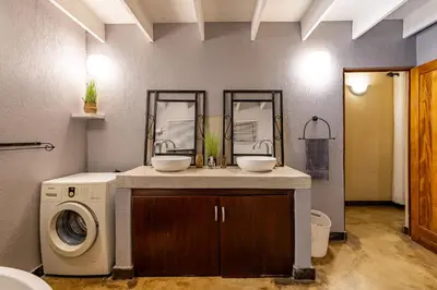 a bathroom with a sink and a washing machine at Hoedspruit Bush Cottage in Hoedspruit