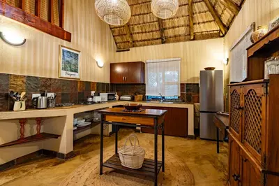 a large kitchen with a table and a refrigerator at Hoedspruit Bush Cottage in Hoedspruit