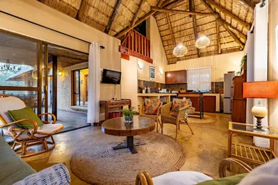 a living room with a table and a kitchen at Hoedspruit Bush Cottage in Hoedspruit