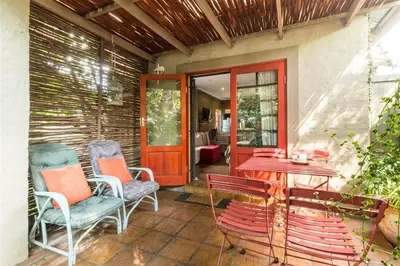 a patio with chairs and a table and a red door at Ambiance Guesthouse in Pretoria