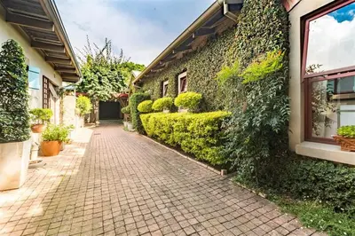 a brick walkway next to a building with plants at Ambiance Guesthouse in Pretoria