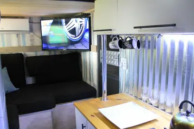 a living room with a table and a tv in a caravan at Ndlovu Tiny Home with a hot tub in Dinokeng in Klipdrift
