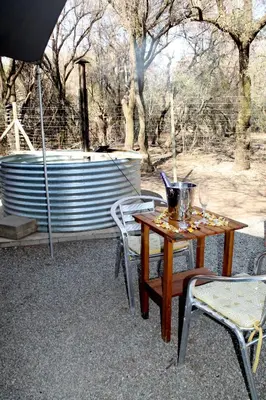 a table and two chairs and a tub with a table and chairs at Ndlovu Tiny Home with a hot tub in Dinokeng in Klipdrift