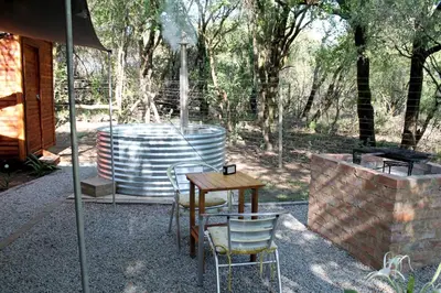 a table and chairs in a patio with a grill at Ndlovu Tiny Home with a hot tub in Dinokeng in Klipdrift