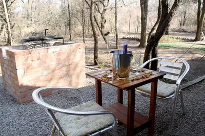 a wooden table with two chairs and a grill at Ndlovu Tiny Home with a hot tub in Dinokeng in Klipdrift