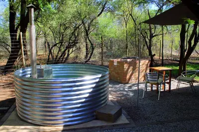 a large metal tub with a table and a chair at Ndlovu Tiny Home with a hot tub in Dinokeng in Klipdrift