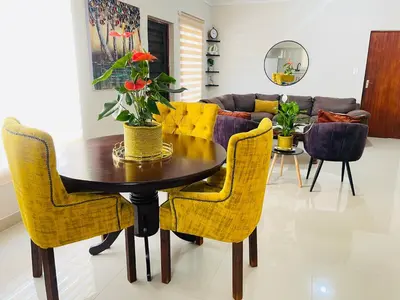 a dining room with a table and yellow chairs at Mnqobi Lifestyle Apartments in Nelspruit