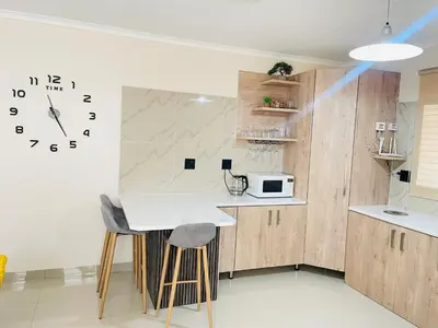 a kitchen with a table and a clock on the wall at Mnqobi Lifestyle Apartments in Nelspruit